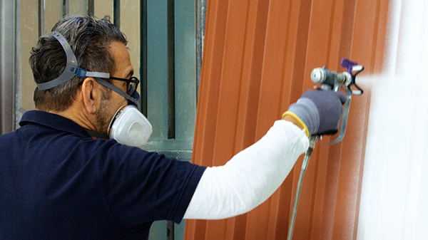 Maler spritzt Lack auf ein Metalltor