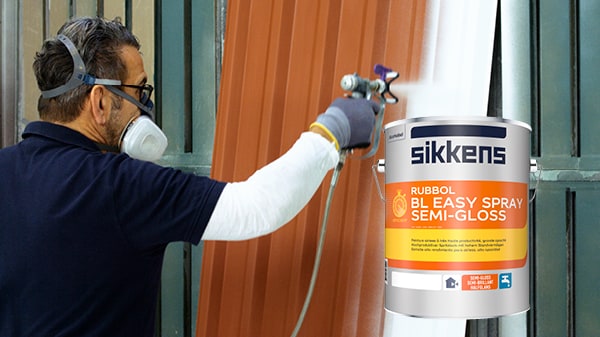 Maler spritzt Lack auf ein Metalltor