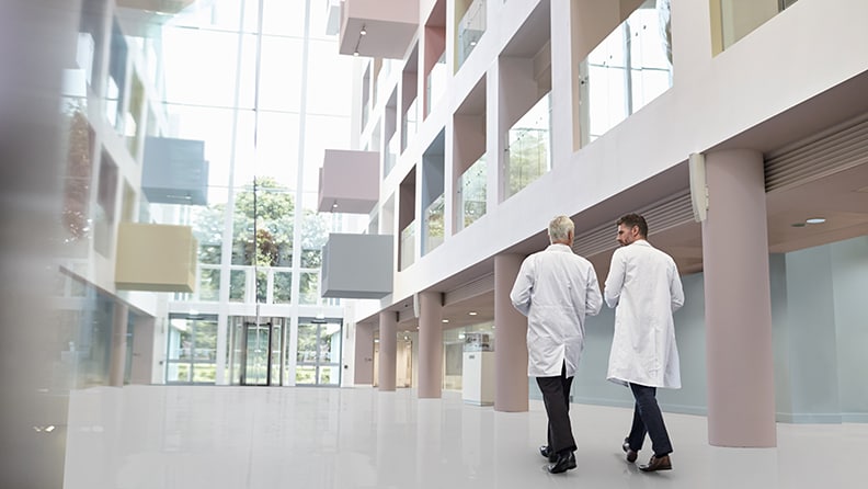 To læger går hen mod døren i et stort atrium