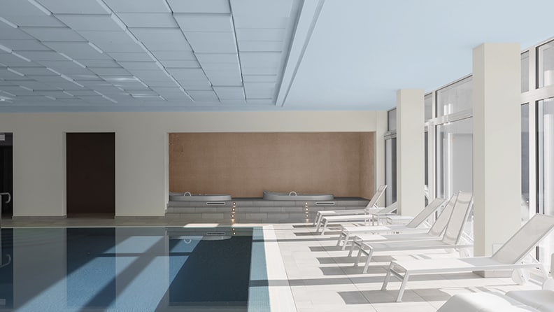 Hotelzwembad met witte ligstoelen en blauw plafond