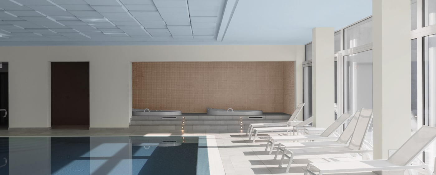 Hotelzwembad met witte ligstoelen en blauw plafond