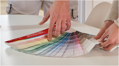  Manos seleccionando colores de una carta cromática para elegir pintura