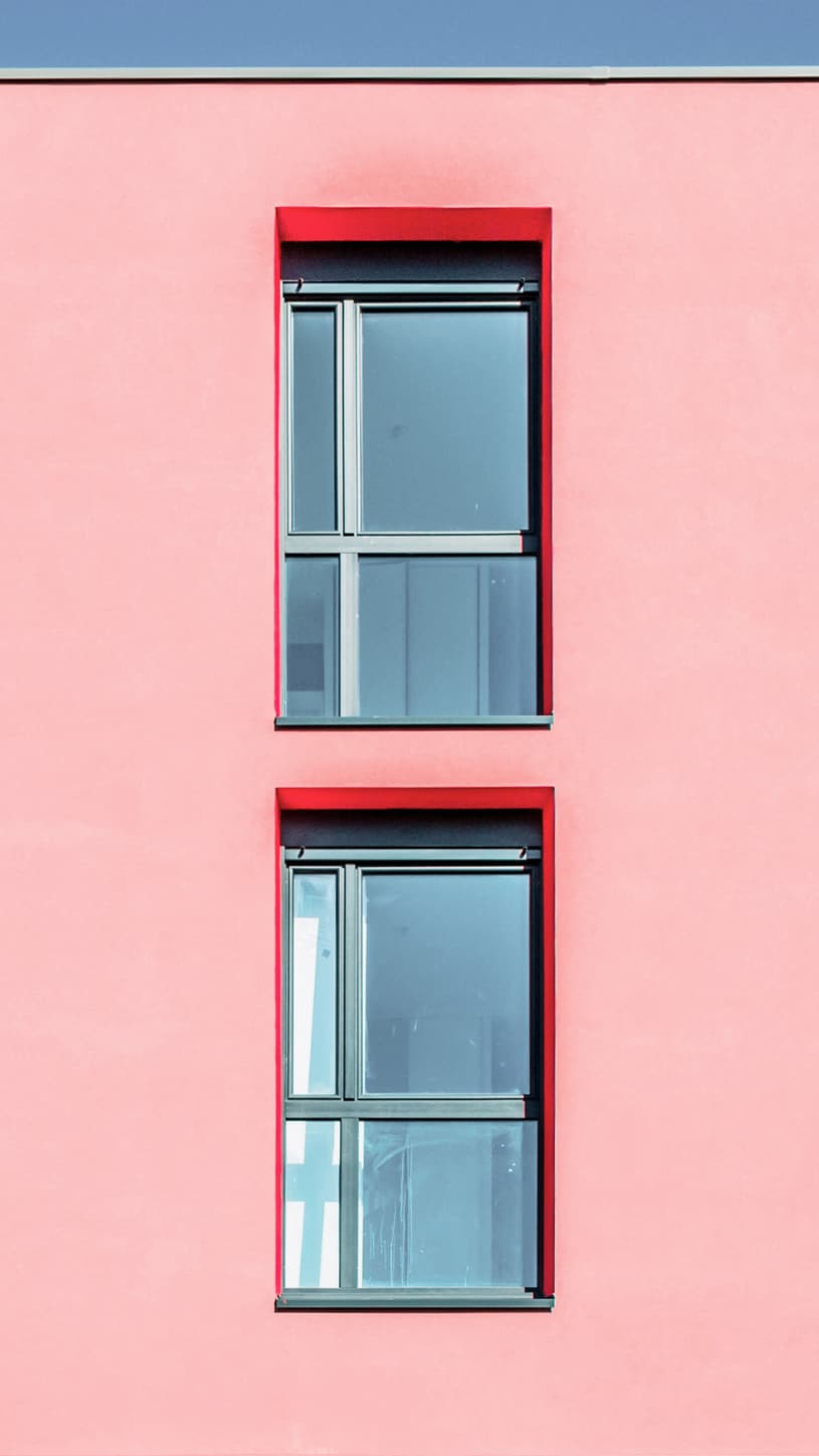 Fachada de edificio rosa con ventanas azules para aplicación de pintura exterior