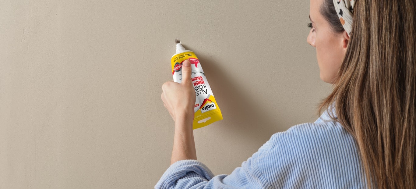 Frau drückt Spachtelmasse aus einer Tube Alleskönner INNEN Champion von Molto in ein Loch in einer Wand