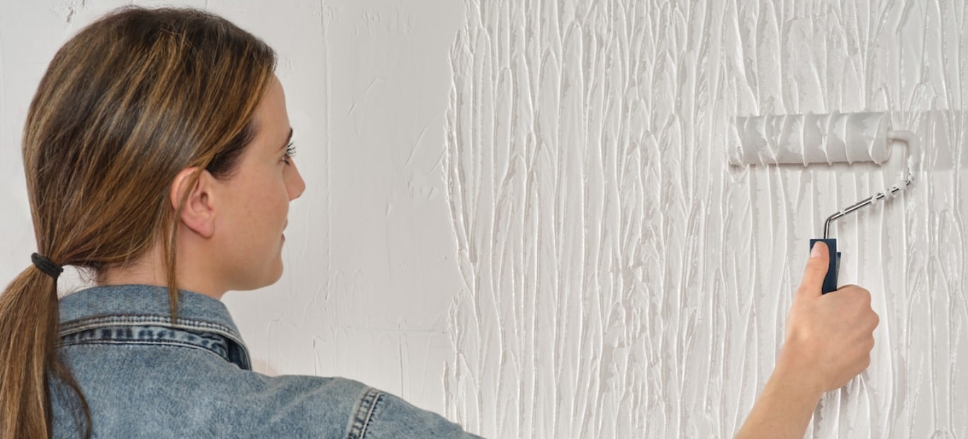 Eine Frau trägt mit einem Farbroller Einfach Glatt von Molto auf eine Wand auf.