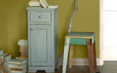 Upgecycelter Schrank und Hocker vor eine schlammgrünen Wand