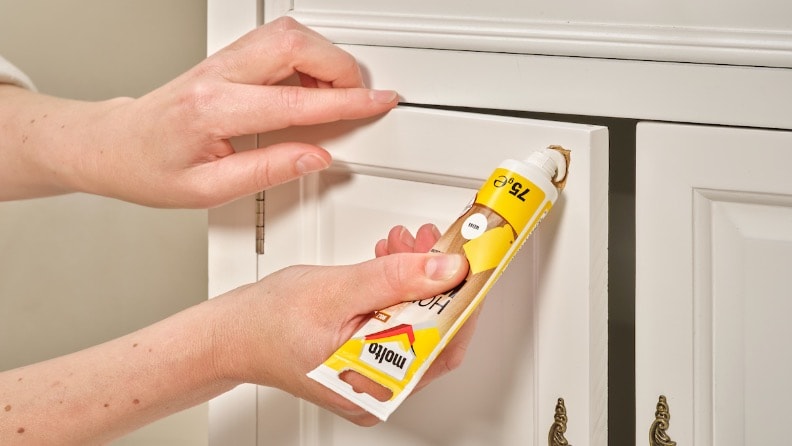 Ein Loch in einer Tür einer Kommode wird mit Holzkitt von Molto aus der Tube gefüllt