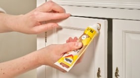 Spachtelmasse wird in eine Schadstelle in einer Holzkommode gefüllt