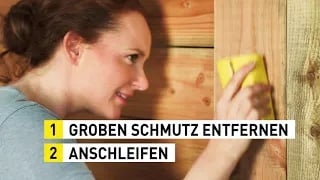 Eine Frau schleift vor dem Lasieren ihres Gartenhauses das Holz ab.