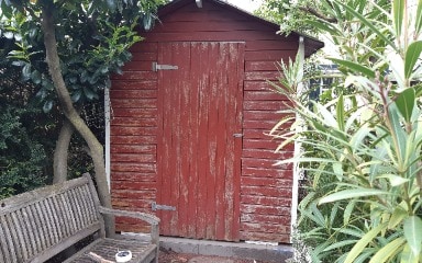 Ein altes Gartenhaus aus Holz, das für die Verwendung mit Consolan abgeschliffen wurde Rückansicht